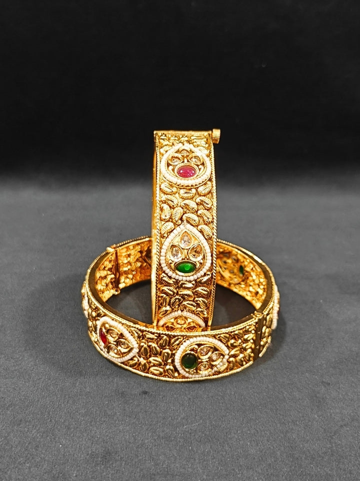 Close-up of an ornate traditional Rajwadi gold Bangle with Bandhai Work, Red & Green Colored Stone and Pearls. Festive celebration look enhanced with statement artificial  Rajwadi bangles. Luxury artificial Rajwadi bangles styled for a wedding function.