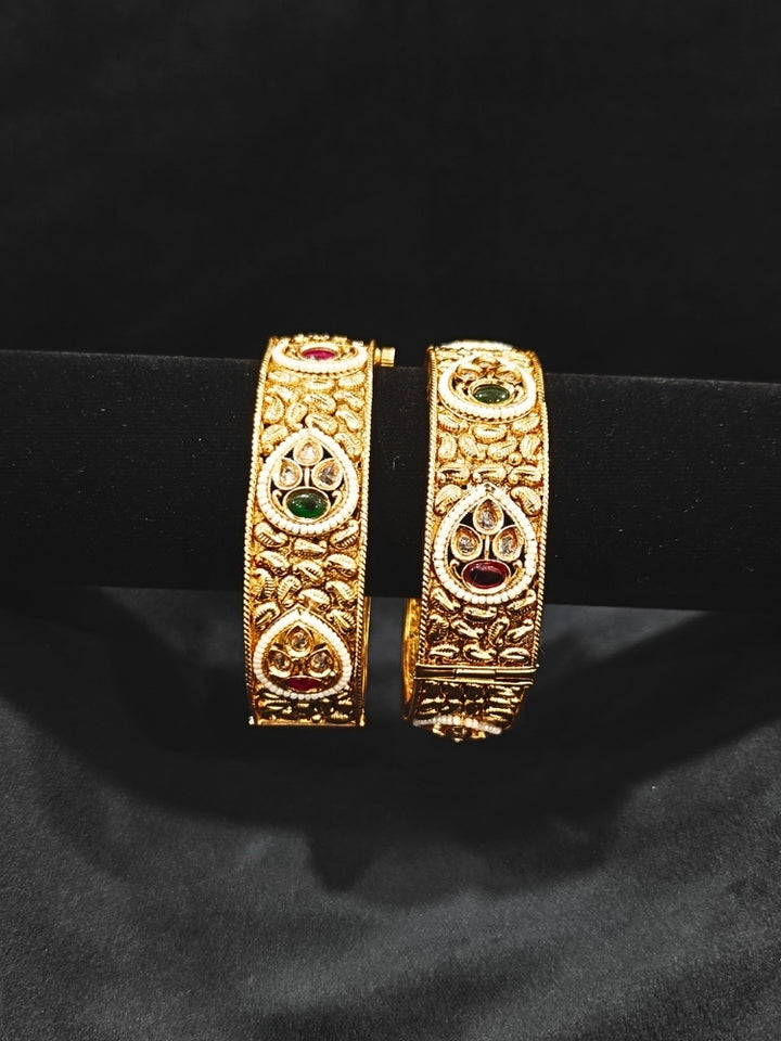 Close-up of an ornate traditional Rajwadi gold Bangle with Bandhai Work, Red & Green Colored Stone and Pearls. Festive celebration look enhanced with statement artificial  Rajwadi bangles. Luxury artificial Rajwadi bangles styled for a wedding function.