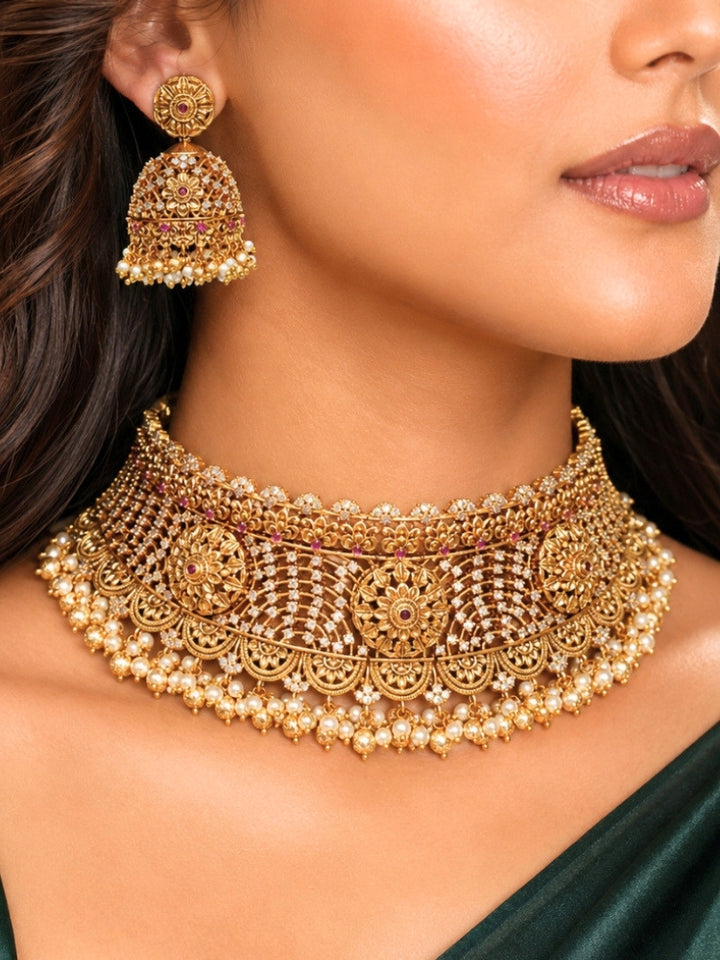 Close-up of a women wearing an ornate traditional (Gold Polish) Choker jewellery set and earrings with Pearls, American Diamond, Colored Stones. Wedding guest outfit enhanced with elegant artificial American Diamond jewelry Set. Close-up shot of a high-quality American diamond artificial necklace worn for festive celebrations.
