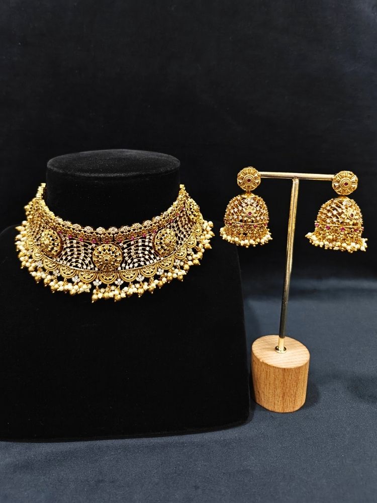 Close-up of an ornate traditional (Gold Polish) Choker jewellery set and earrings with Pearls, American Diamond, Colored Stones. Wedding guest outfit enhanced with elegant artificial American Diamond jewelry Set. Close-up shot of a high-quality American diamond artificial necklace worn for festive celebrations.