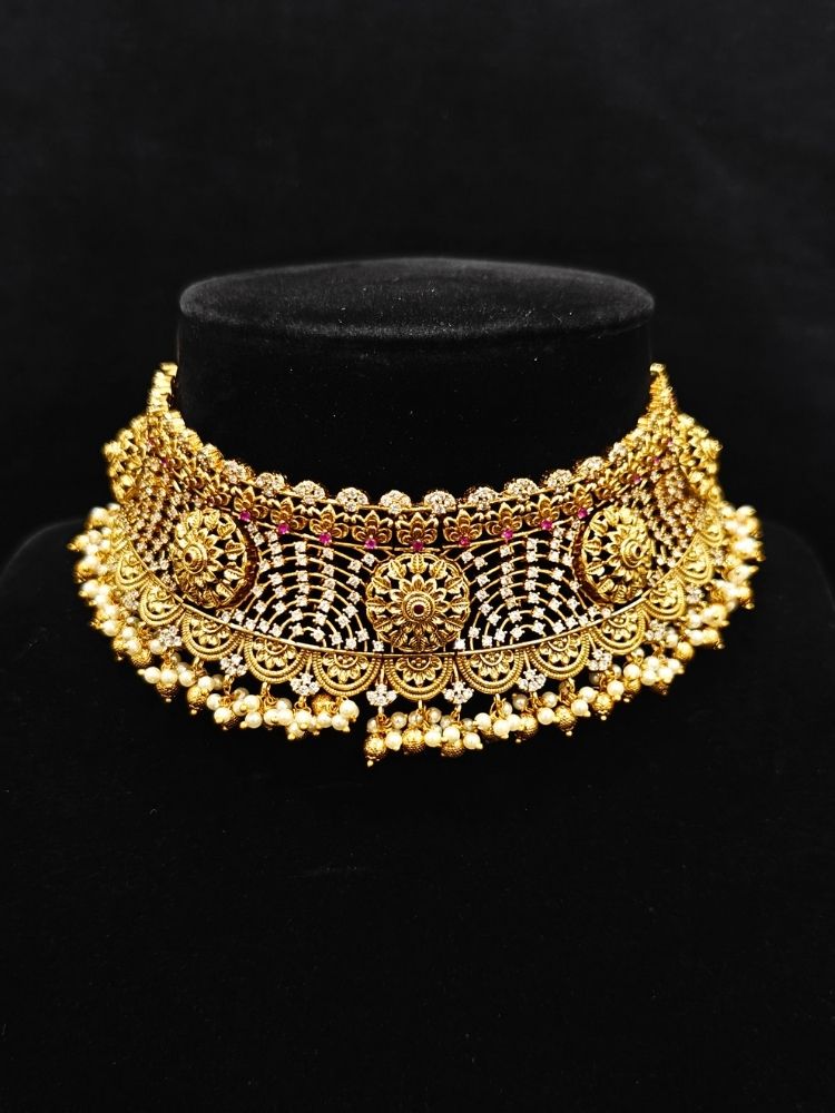 Close-up of an ornate traditional (Gold Polish) Choker jewellery set and earrings with Pearls, American Diamond, Colored Stones. Wedding guest outfit enhanced with elegant artificial American Diamond jewelry Set. Close-up shot of a high-quality American diamond artificial necklace worn for festive celebrations.