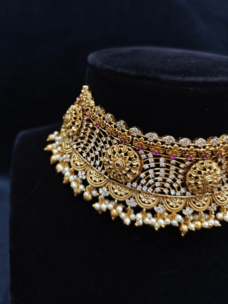 Close-up of an ornate traditional (Gold Polish) Choker jewellery set and earrings with Pearls, American Diamond, Colored Stones. Wedding guest outfit enhanced with elegant artificial American Diamond jewelry Set. Close-up shot of a high-quality American diamond artificial necklace worn for festive celebrations.
