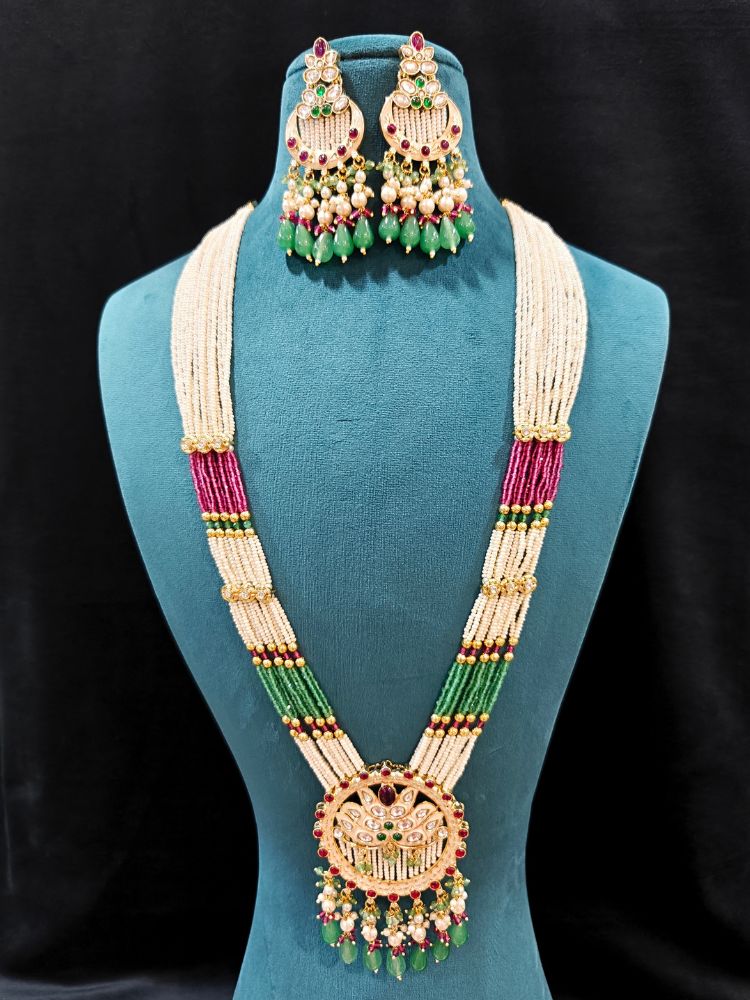 Close-up of an ornate traditional Mint Pink and Green Rajwadi gold Long jewellery set and earrings  with Pearls, Moissanite Kundan, Bandhai Work, Hydro Crystals and Tumble Beads. Mehendi ceremony look styled with a Rajwadi artificial jewelry set. Traditional Indian look featuring a Rajwadi necklace set.