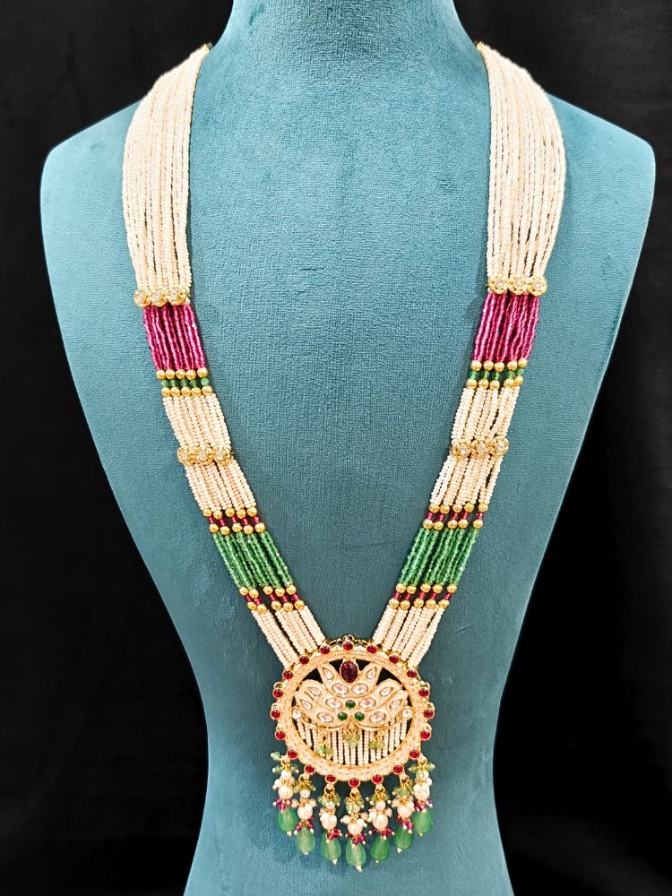 Close-up of an ornate traditional Mint Pink and Green Rajwadi gold Long jewellery set and earrings  with Pearls, Moissanite Kundan, Bandhai Work, Hydro Crystals and Tumble Beads. Mehendi ceremony look styled with a Rajwadi artificial jewelry set. Traditional Indian look featuring a Rajwadi necklace set.
