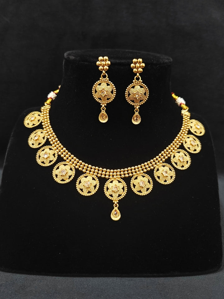 Close-up of an ornate traditional (Gold Polish) Collar jewellery set and earrings with American Diamond. Saree look completed with elegant artificial American Diamond jewelry for festive occasions. Woman wearing trending artificial American Diamond jewelry for wedding season in India.