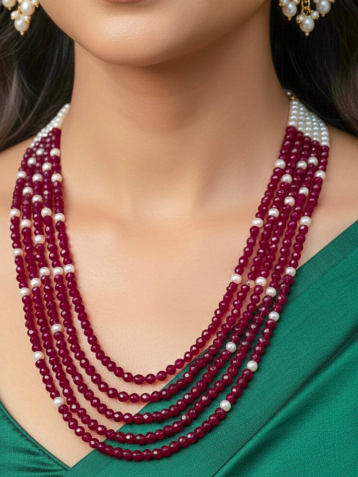 Close-up of a woman wearing an ornate traditional Red & White Layered Jewellery set and Earring with Kundan, Colored Stones, Pearls and Crystal Beads. Mehendi ceremony look completed with a handcrafted Pearl jewelry set. Mehendi ceremony look completed with a handcrafted Pearl jewelry set.