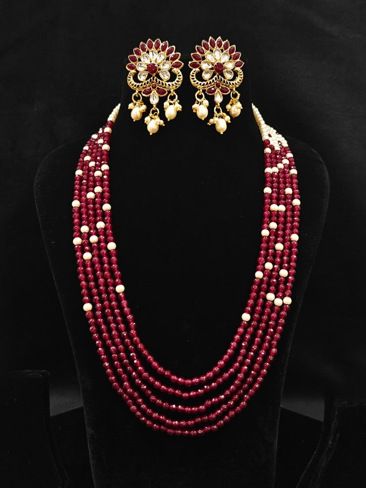 Close-up of an ornate traditional Red & White Layered Jewellery set and Earring with Kundan, Colored Stones, Pearls and Crystal Beads. Mehendi ceremony look completed with a handcrafted Pearl jewelry set. Mehendi ceremony look completed with a handcrafted Pearl jewelry set.