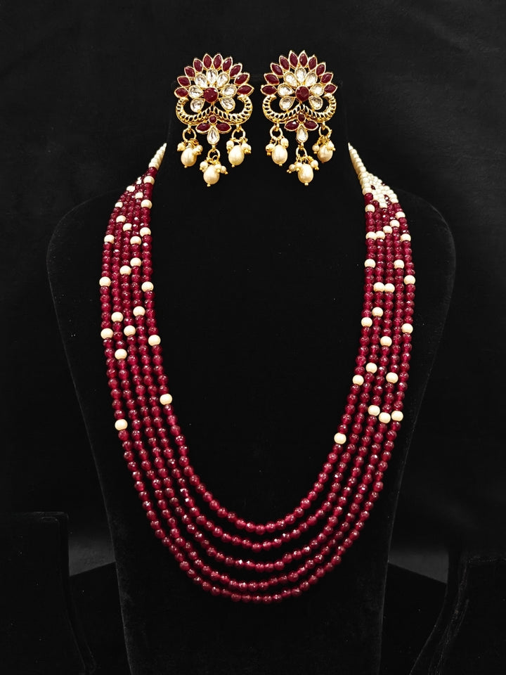 Close-up of an ornate traditional Red & White Layered Jewellery set and Earring with Kundan, Colored Stones, Pearls and Crystal Beads. Mehendi ceremony look completed with a handcrafted Pearl jewelry set. Mehendi ceremony look completed with a handcrafted Pearl jewelry set.