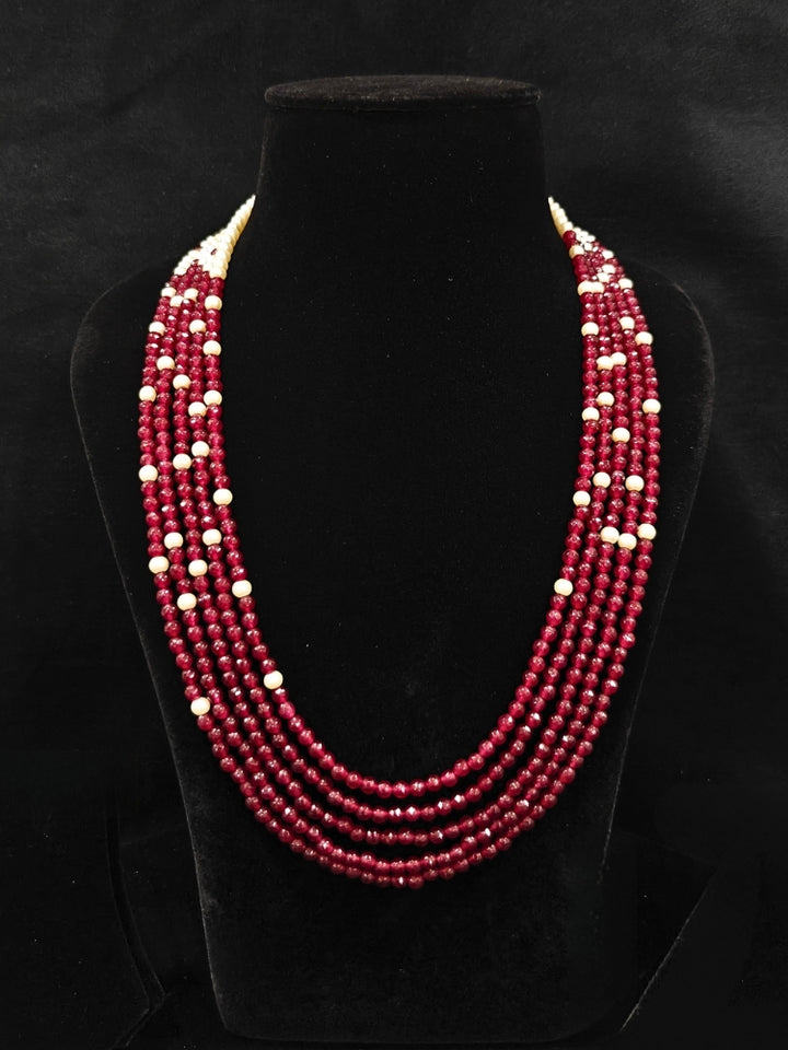 Close-up of an ornate traditional Red & White Layered Jewellery set and Earring with Kundan, Colored Stones, Pearls and Crystal Beads. Mehendi ceremony look completed with a handcrafted Pearl jewelry set. Mehendi ceremony look completed with a handcrafted Pearl jewelry set.