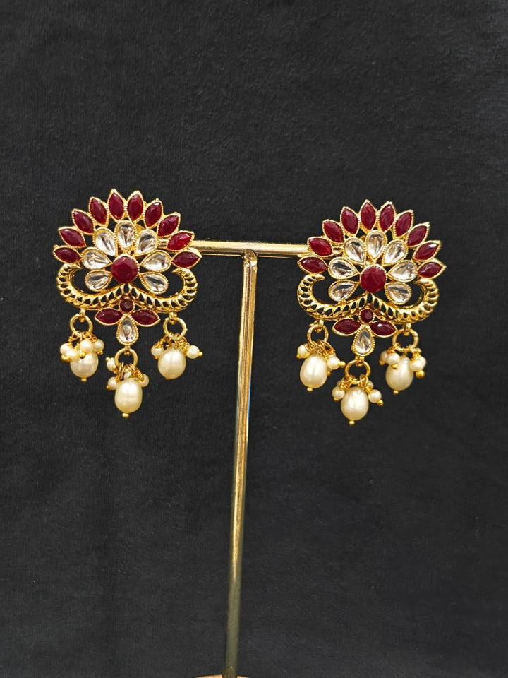 Close-up of an ornate traditional Red & White Layered Jewellery set and Earring with Kundan, Colored Stones, Pearls and Crystal Beads. Mehendi ceremony look completed with a handcrafted Pearl jewelry set. Mehendi ceremony look completed with a handcrafted Pearl jewelry set.