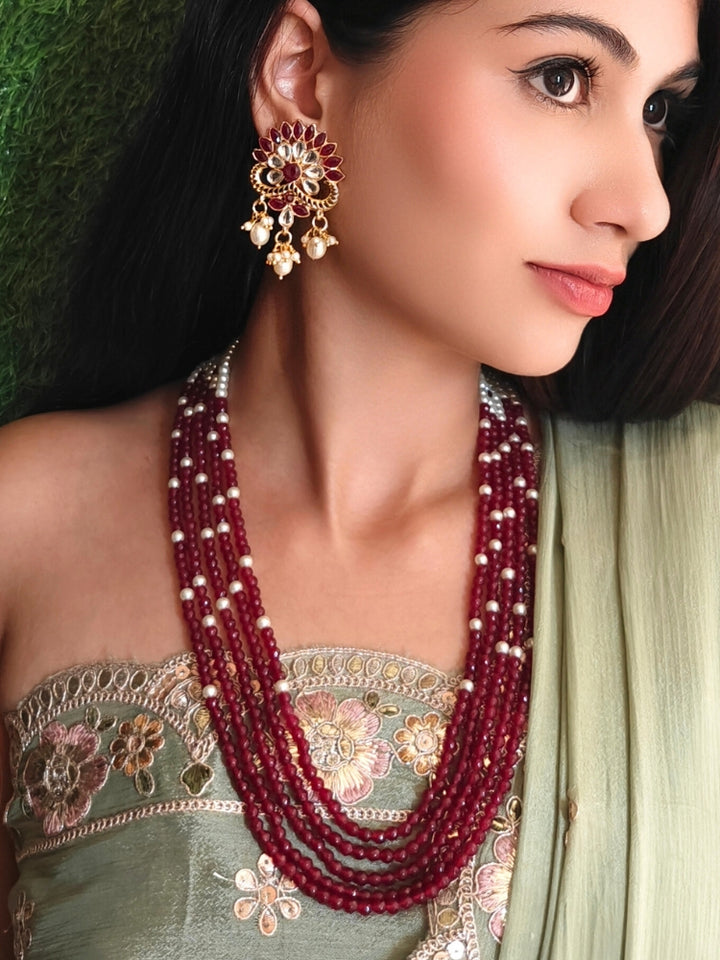 Close-up of a woman wearing an ornate traditional Red & White Layered Jewellery set and Earring with Kundan, Colored Stones, Pearls and Crystal Beads. Mehendi ceremony look completed with a handcrafted Pearl jewelry set. Mehendi ceremony look completed with a handcrafted Pearl jewelry set.