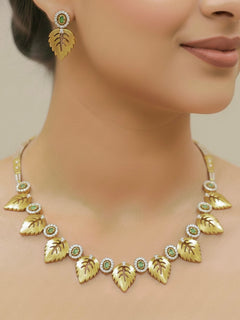 Close-up of a woman wearing an ornate Indo-Western (Gold Polish) Collar jewellery set and earrings with American Diamond and Green Colored Stones. Indo-western outfit styled with modern American Diamond artificial jewelry. Elegant Indian wedding look completed with luxury artificial American Diamond jewelry.