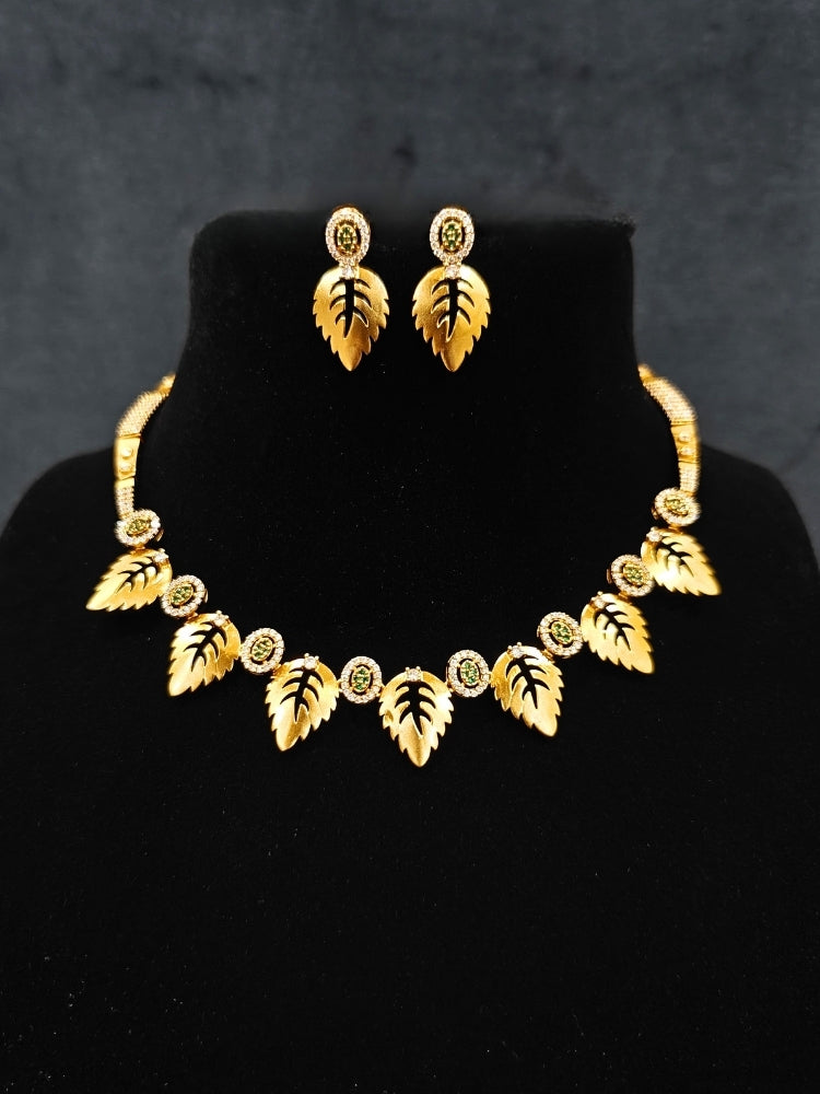 Close-up of an ornate Indo-Western (Gold Polish) Collar jewellery set and earrings with American Diamond and Green Colored Stones. Indo-western outfit styled with modern American Diamond artificial jewelry. Elegant Indian wedding look completed with luxury artificial American Diamond jewelry.