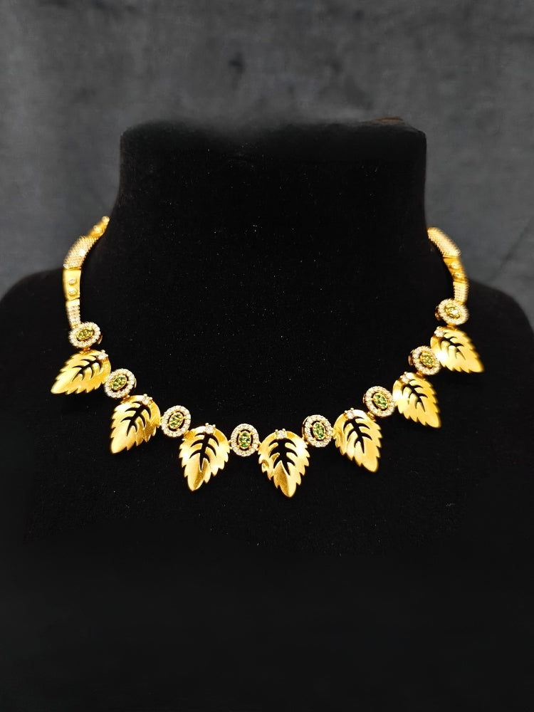 Close-up of an ornate Indo-Western (Gold Polish) Collar jewellery set and earrings with American Diamond and Green Colored Stones. Indo-western outfit styled with modern American Diamond artificial jewelry. Elegant Indian wedding look completed with luxury artificial American Diamond jewelry.