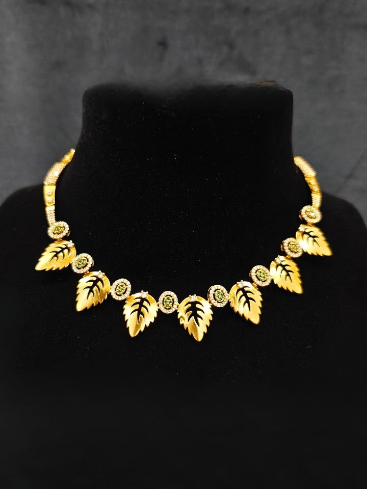 Close-up of an ornate Indo-Western (Gold Polish) Collar jewellery set and earrings with American Diamond and Green Colored Stones. Indo-western outfit styled with modern American Diamond artificial jewelry. Elegant Indian wedding look completed with luxury artificial American Diamond jewelry.