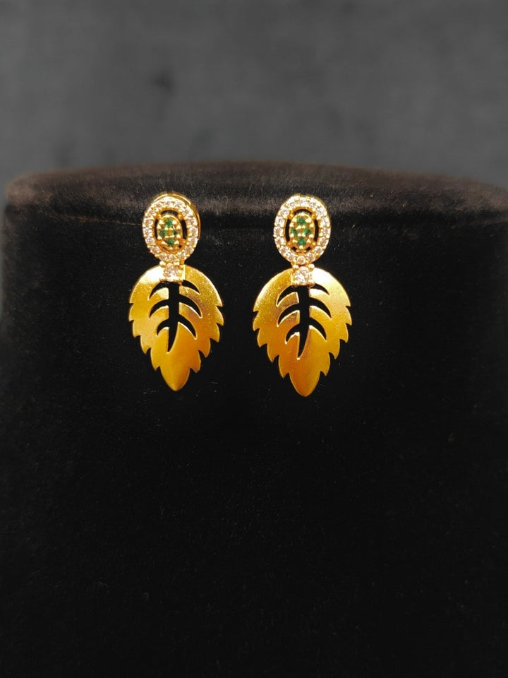 Close-up of an ornate Indo-Western (Gold Polish) Collar jewellery set and earrings with American Diamond and Green Colored Stones. Indo-western outfit styled with modern American Diamond artificial jewelry. Elegant Indian wedding look completed with luxury artificial American Diamond jewelry.