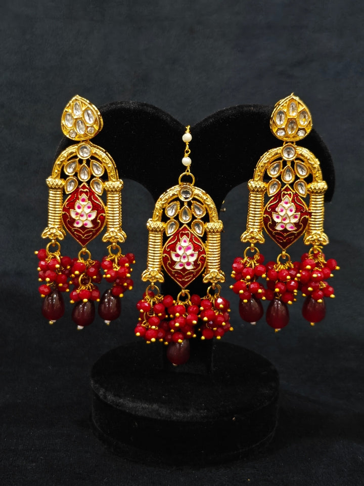 Close-up of an ornate traditional (Gold Polish) Maroon Choker jewellery set and earrings and maangtikka with Kundan, Meenakari, Crystal beads and Tumble beads. Close-up of intricate Kundan craftsmanship in artificial bridal jewelry. A traditional Kundan artificial necklace set for her wedding ceremony.