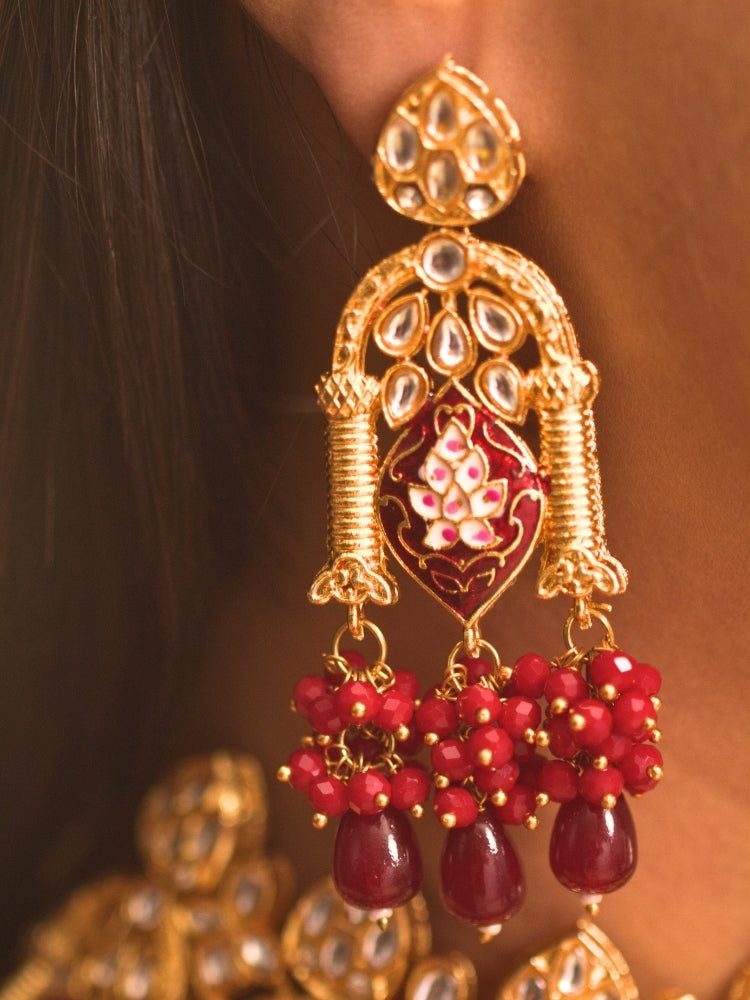 Close-up of a woman wearing an ornate traditional (Gold Polish) Maroon Choker jewellery set and earrings and maangtikka with Kundan, Meenakari, Crystal beads and Tumble beads. Close-up of intricate Kundan craftsmanship in artificial bridal jewelry. Bride wearing a traditional Kundan artificial necklace set for her wedding ceremony.
