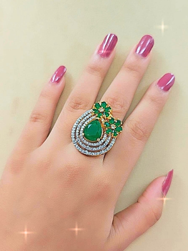 The Meadow Green Ring is an adjustable Cocktail Ring featuring a large Green gemstone center, American diamonds in three concentric circles, and Green stone flowers, showcased on a girls hand. 
