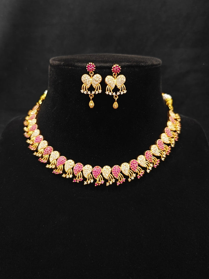 Close-up of an ornate Traditional Pink & White (Gold Polish)  Collar Necklace Set and earrings with American Diamonds and Colored Stones. Mehendi function outfit styled with a lightweight Diamond necklace. Wedding guest styling a statement American Diamond artificial necklace.