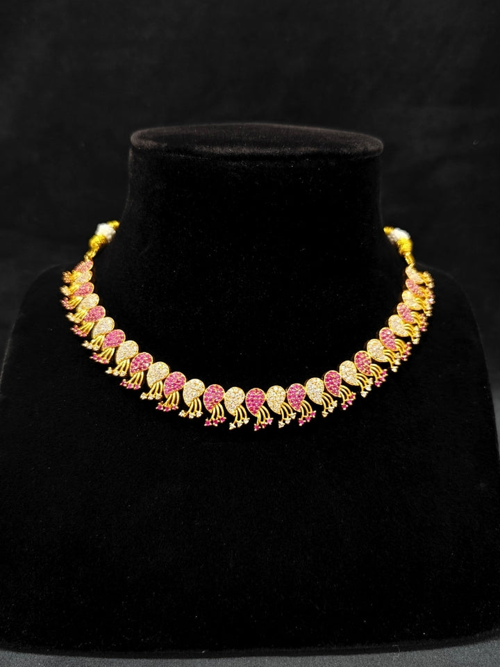 Close-up of an ornate Traditional Pink & White (Gold Polish)  Collar Necklace Set and earrings with American Diamonds and Colored Stones. Mehendi function outfit styled with a lightweight Diamond necklace. Wedding guest styling a statement American Diamond artificial necklace.