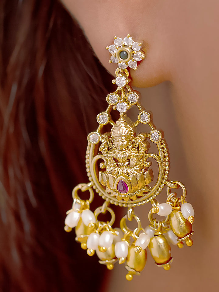 A woman models the Meherin Choker Necklace Set—an elegant gold choker necklace set with jali work along with american diamonds and Goddess Laxmi circumfrencing the bottom, along with matching earrings —paired with a pink outfit. Only her lower face is shown, emphasizing the set’s intricate design.