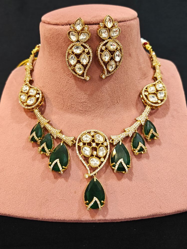 Close-up of an ornate traditional American Diamond gold Collar Green jewellery set and earrings with Green Colored Stones and American Diamond. Close-up of a featuring an anti-tarnish American diamond artificial necklace. Perfect American Diamond necklace set for weddings and festivals.