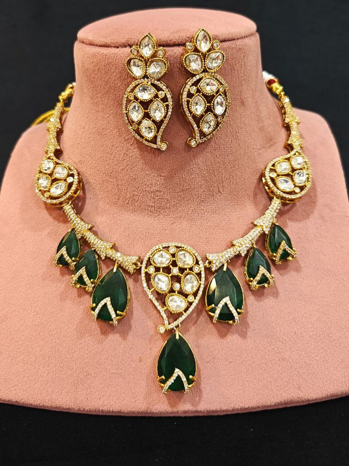 Close-up of an ornate traditional American Diamond gold Collar Green jewellery set and earrings with Green Colored Stones and American Diamond. Close-up of a featuring an anti-tarnish American diamond artificial necklace. Perfect American Diamond necklace set for weddings and festivals.