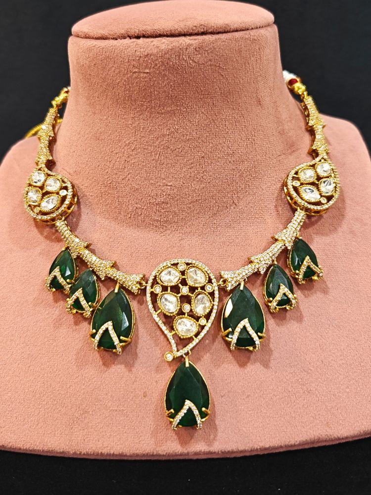 Close-up of an ornate traditional American Diamond gold Collar Green jewellery set and earrings with Green Colored Stones and American Diamond. Close-up of a featuring an anti-tarnish American diamond artificial necklace. Perfect American Diamond necklace set for weddings and festivals.