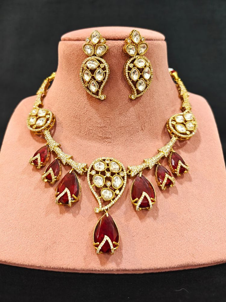 Close-up of an ornate traditional American Diamond gold Collar Red jewellery set and earrings with Red Colored Stones and American Diamond. Close-up of a featuring an anti-tarnish American diamond artificial necklace. Perfect American Diamond necklace set for weddings and festivals.