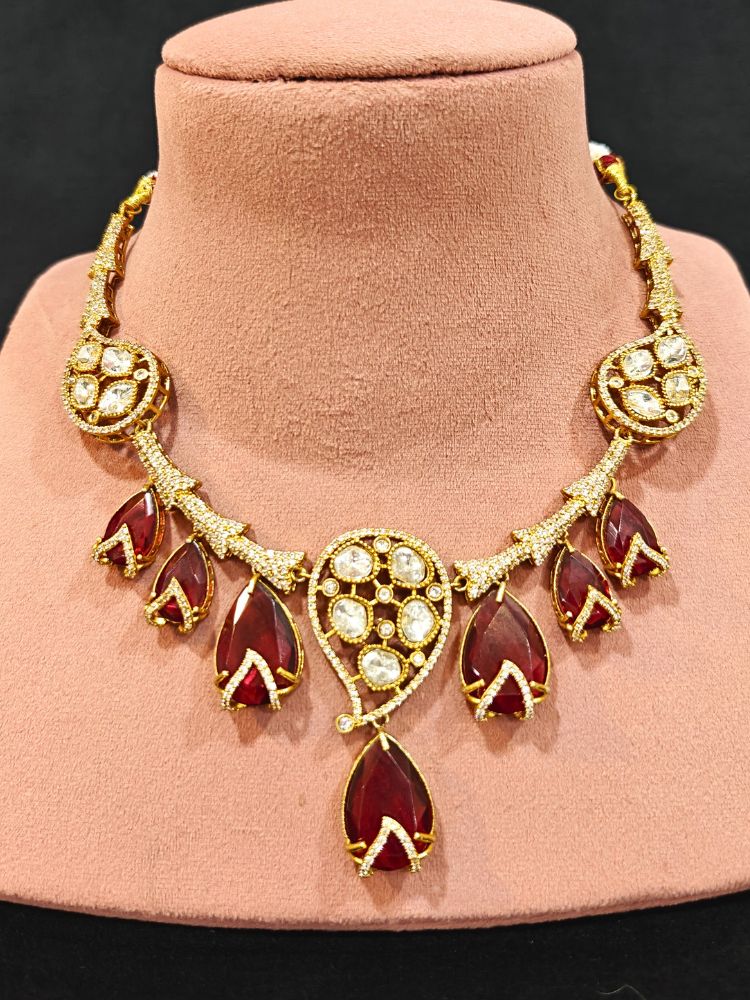 Close-up of an ornate traditional American Diamond gold Collar Red jewellery set and earrings with Red Colored Stones and American Diamond. Close-up of a featuring an anti-tarnish American diamond artificial necklace. Perfect American Diamond necklace set for weddings and festivals.