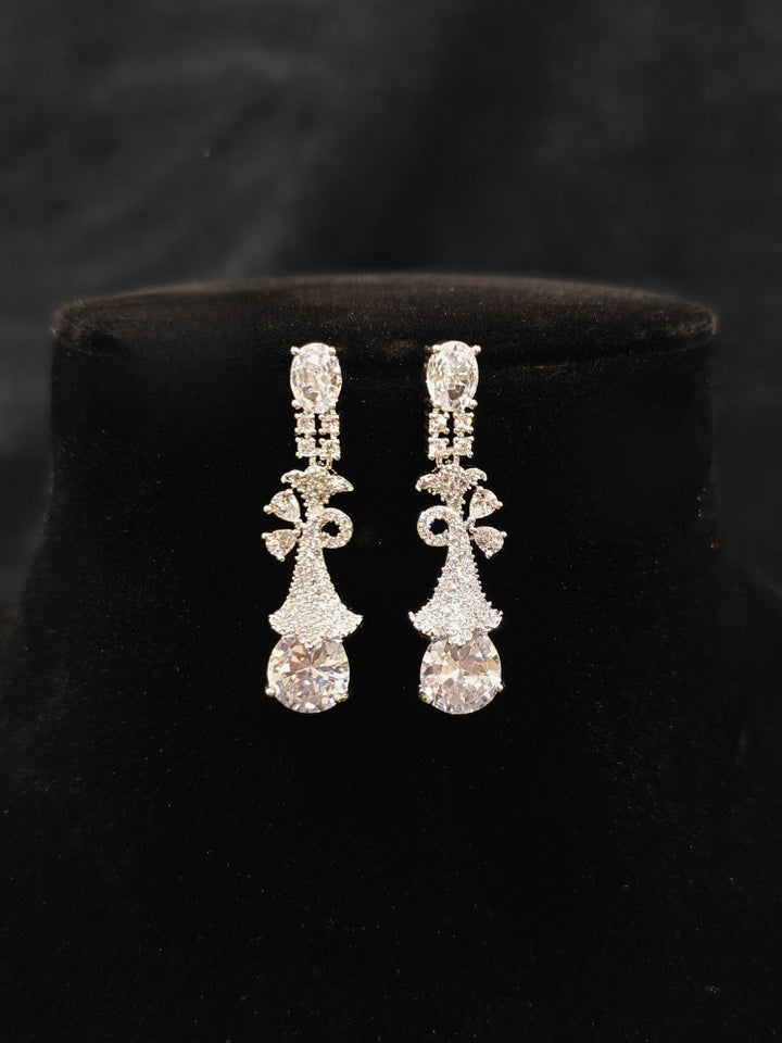 Close-up of an ornate Western White (Silver Polish) Collar jewellery set and earrings with American Diamonds. Close-up of a cocktail party look featuring a premium American diamond necklace. Party wear outfit completed with a lightweight American diamond necklace.