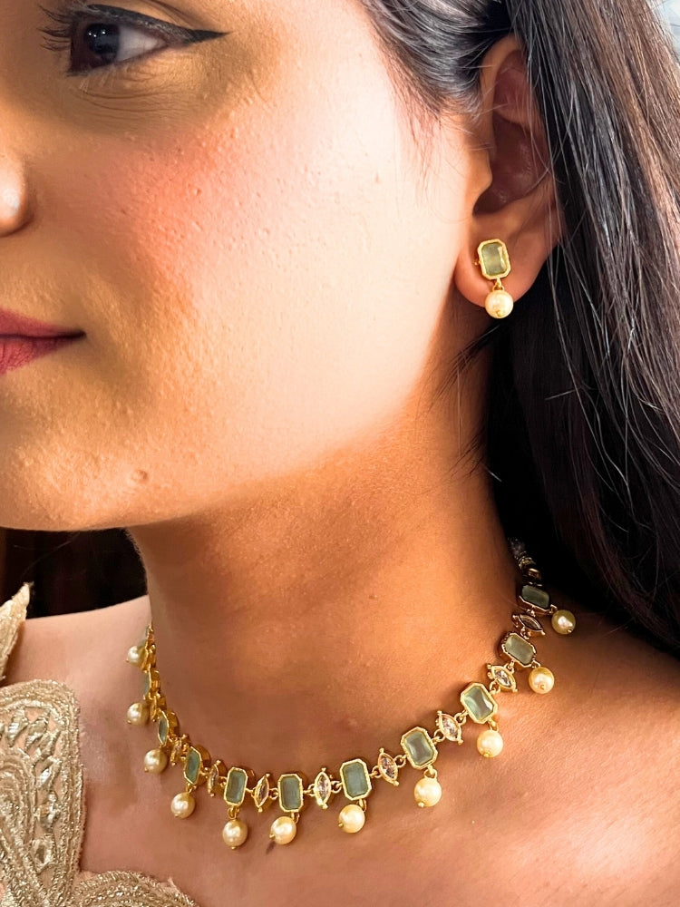 Close-up of a woman wearing the Mint Green Amelia Choker Necklace adorned with colored gemstones and dangling pearls, matching earrings, and a Mint Green top—an elegant choice for wedding ceremonies. Her lips are lightly colored, with dark hair partially visible.