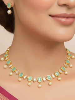 Close-up of a woman wearing an ornate traditional (Gold Polish) Mint Green Choker jewellery set and earrings with Colored Stones, Pearl and American Diamonds. Festive Diwali outfit styled with an Colored Stones artificial necklace. Mehendi function outfit styled with a Colored Stone  necklace set.