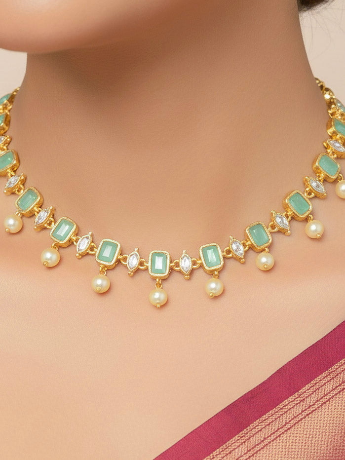 Close-up of a woman wearing an ornate traditional (Gold Polish) Mint Green Choker jewellery set and earrings with Colored Stones, Pearl and American Diamonds. Festive Diwali outfit styled with an Colored Stones artificial necklace. Mehendi function outfit styled with a Colored Stone  necklace set.