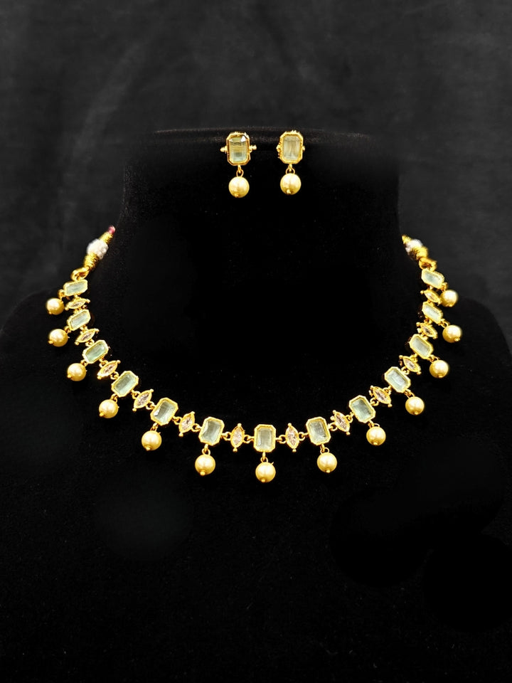 Close-up of an ornate traditional (Gold Polish) Mint Green Choker jewellery set and earrings with Colored Stones, Pearl and American Diamonds. Festive Diwali outfit styled with an Colored Stones artificial necklace. Mehendi function outfit styled with a Colored Stone  necklace set.