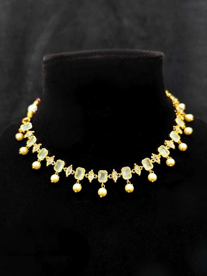 Close-up of an ornate traditional (Gold Polish) Mint Green Choker jewellery set and earrings with Colored Stones, Pearl and American Diamonds. Festive Diwali outfit styled with an Colored Stones artificial necklace. Mehendi function outfit styled with a Colored Stone  necklace set.