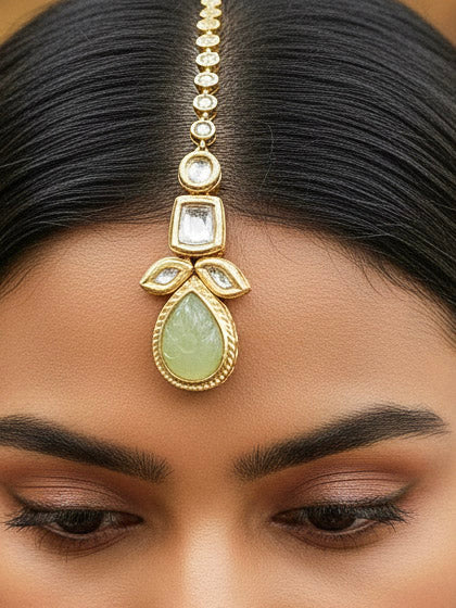 Close-up of a woman wearing an ornate traditional (Gold Polish) Mint Green Long Kundan jewellery set and earrings and a Choker and Mangtikka with Kundan and Colored Stones. Wedding celebration look enhanced with a statement Kundan necklace. Bride wearing a royal Kundan artificial necklace for wedding rituals.