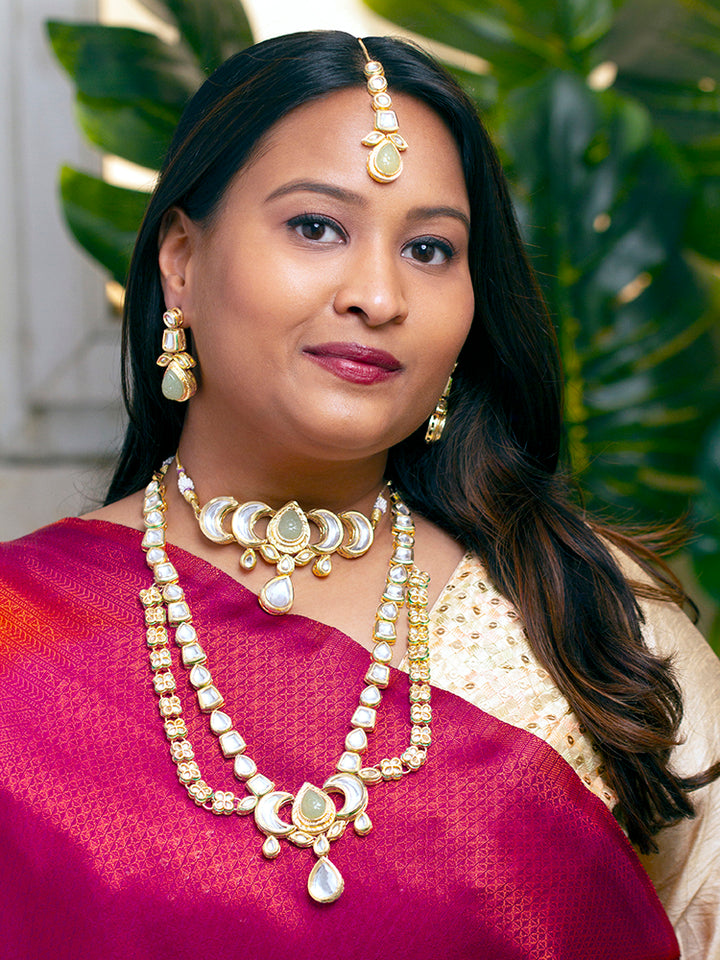 Close-up of a woman wearing an ornate traditional (Gold Polish) Mint Green Long Kundan jewellery set and earrings and a Choker and Mangtikka with Kundan and Colored Stones. Wedding celebration look enhanced with a statement Kundan necklace. Bride wearing a royal Kundan artificial necklace for wedding rituals.