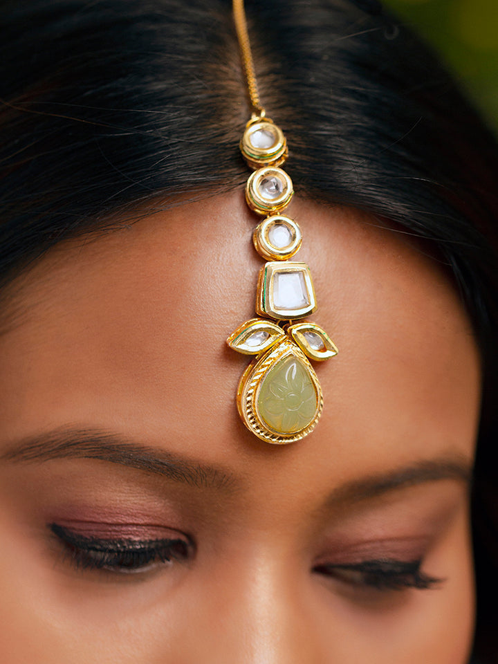 Close-up of a woman wearing an ornate traditional (Gold Polish) Mint Green Long Kundan jewellery set and earrings and a Choker and Mangtikka with Kundan and Colored Stones. Wedding celebration look enhanced with a statement Kundan necklace. Bride wearing a royal Kundan artificial necklace for wedding rituals.