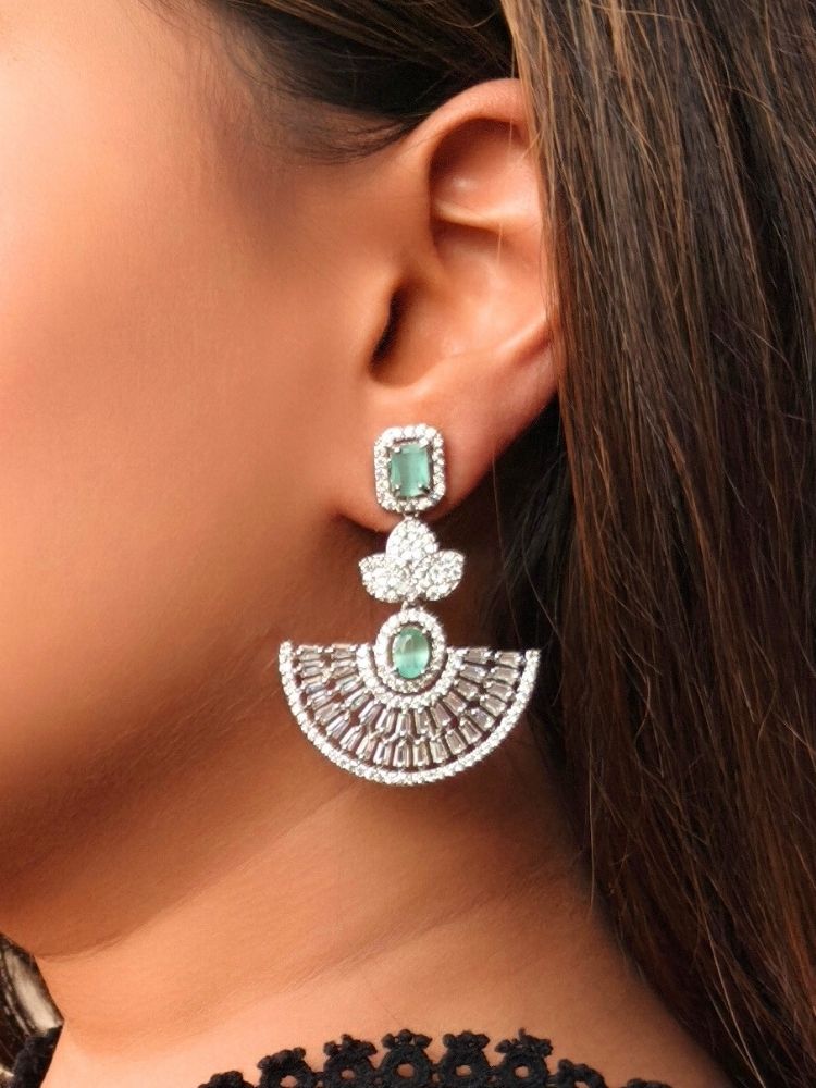 Close-up of a woman wearing an ornate Western (Silver Polish) Mint Green Diamond Earrings with American Diamond and Colored Stones. Reception-ready look featuring a statement American diamond Earrings set. Elegant wedding jewelry look featuring a premium artificial American diamond Earrings.