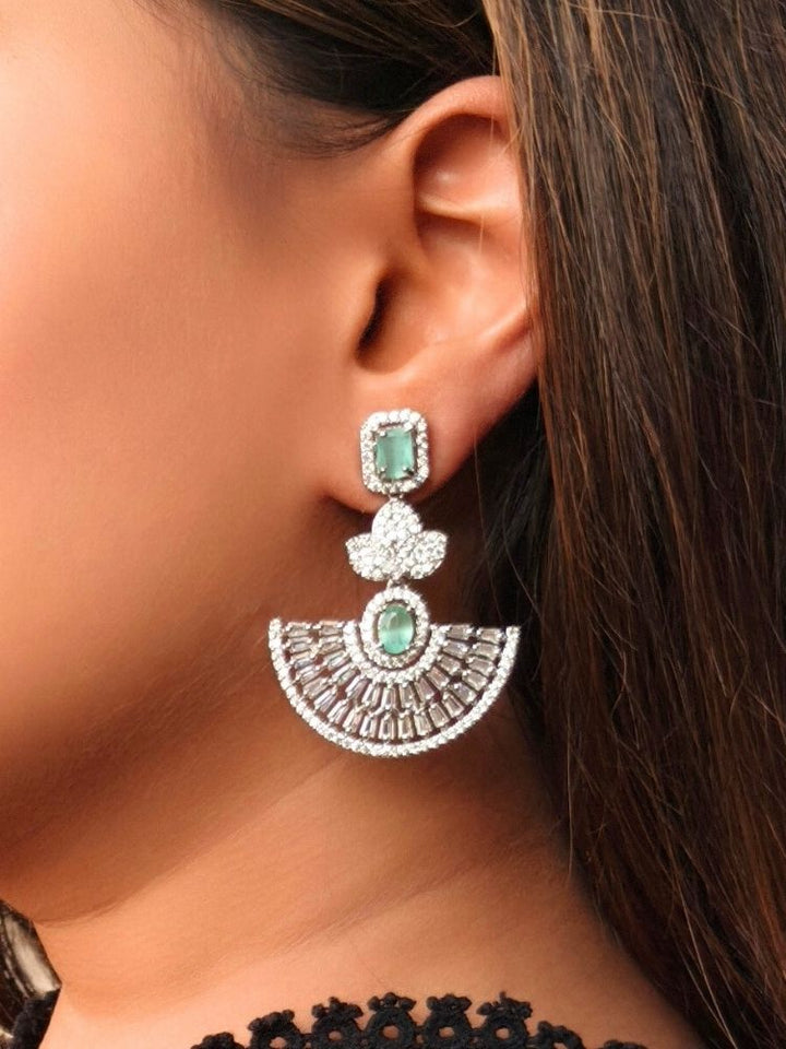 Close-up of a woman wearing an ornate Western (Silver Polish) Mint Green Diamond Earrings with American Diamond and Colored Stones. Reception-ready look featuring a statement American diamond Earrings set. Elegant wedding jewelry look featuring a premium artificial American diamond Earrings.