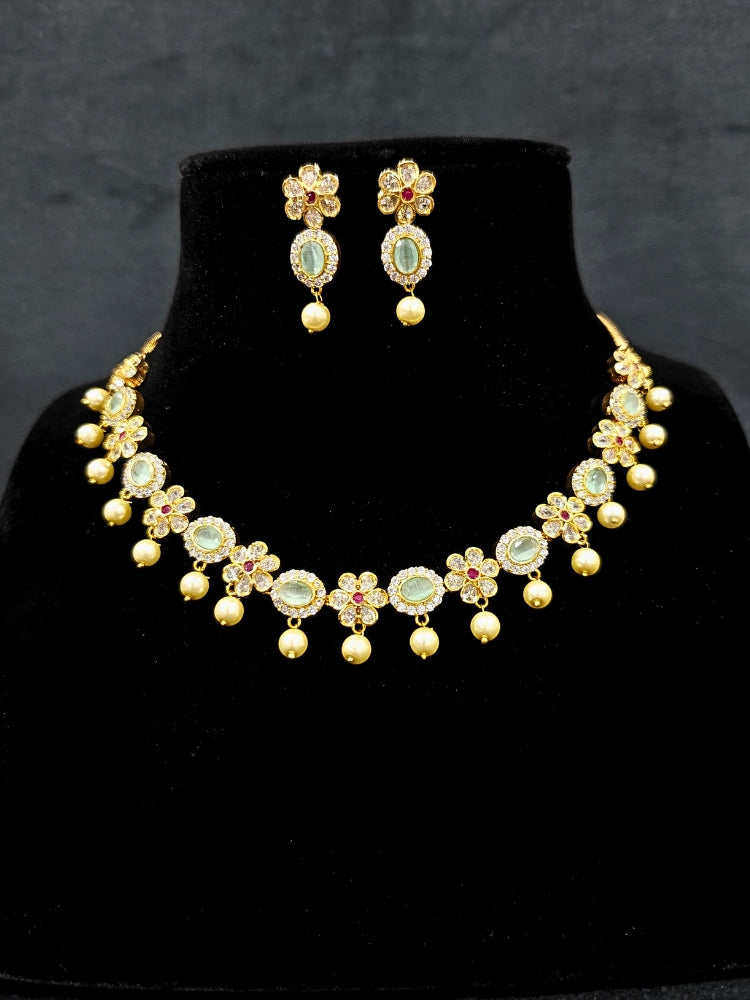 Close-up of an ornate traditional Mint Green (gold Polish) Collar jewellery set and earrings with American diamonds, Pearls and Colored Stones. Festive Diwali outfit styled with an American diamond artificial necklace. Elegant wedding jewelry look featuring a premium artificial American diamond necklace. 