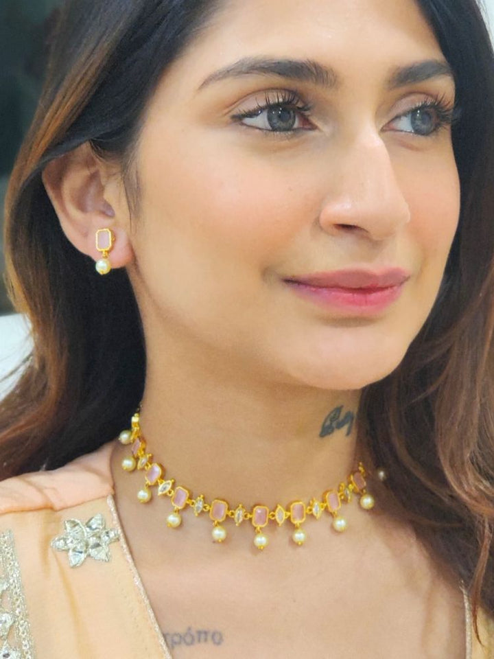 A girl looking at the camera wearing The Mint Pink Amelia Choker Necklace Set features mint pink colored stones and dangling pearls, with matching stud earrings. 