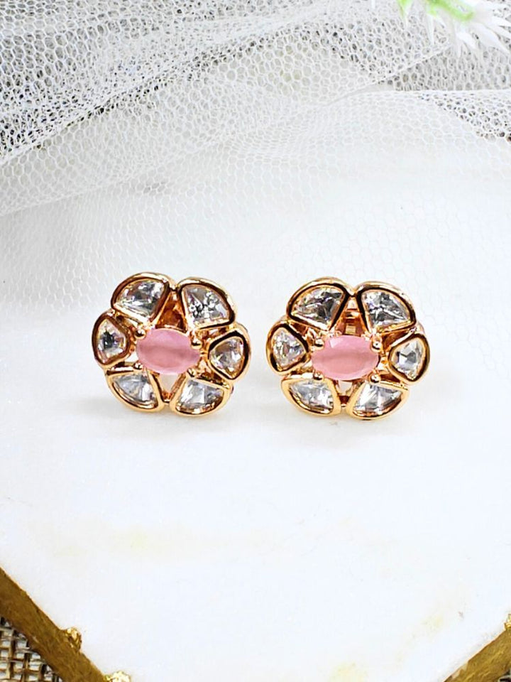 The Mint Pink Daffodil stud Earrings feature gold flower-shaped brass settings with clear American Diamond petals and a Mint Pink stone center, displayed on a white surface with sheer white fabric in the background.