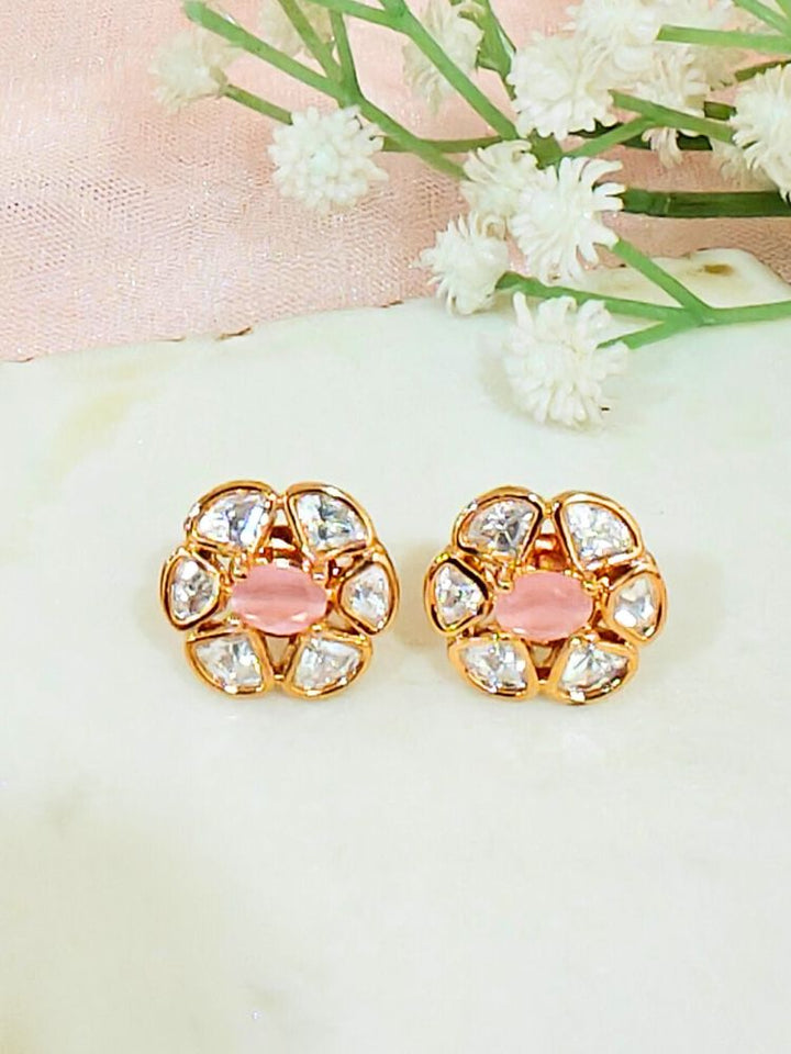 The Mint Pink Daffodil stud Earrings feature gold flower-shaped brass settings with clear American Diamond petals and a Mint Pink stone center, displayed on a white surface with sheer white fabric in the background