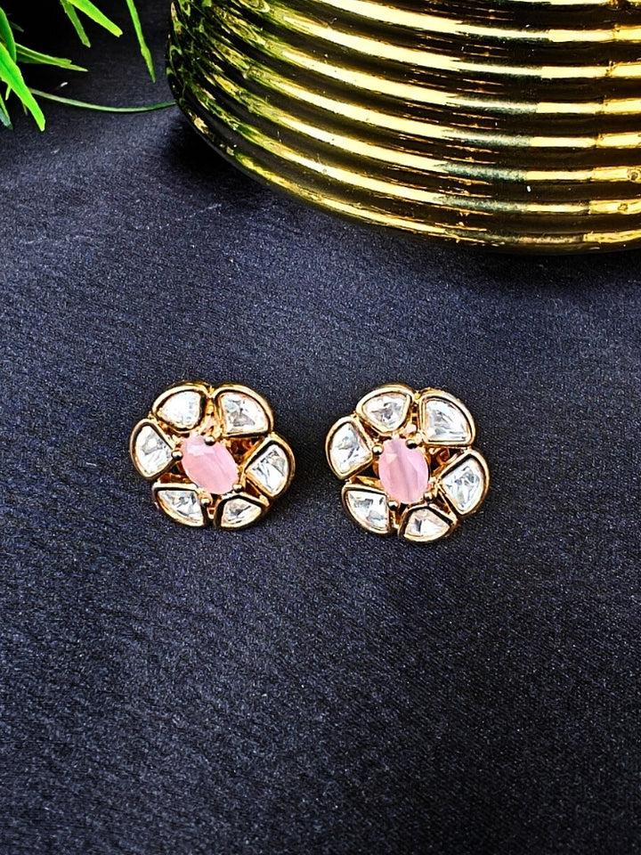 The Mint Pink Daffodil stud Earrings feature gold flower-shaped brass settings with clear American Diamond petals and a Mint Pink stone center, displayed on a Black surface with Golden Aceent in the background