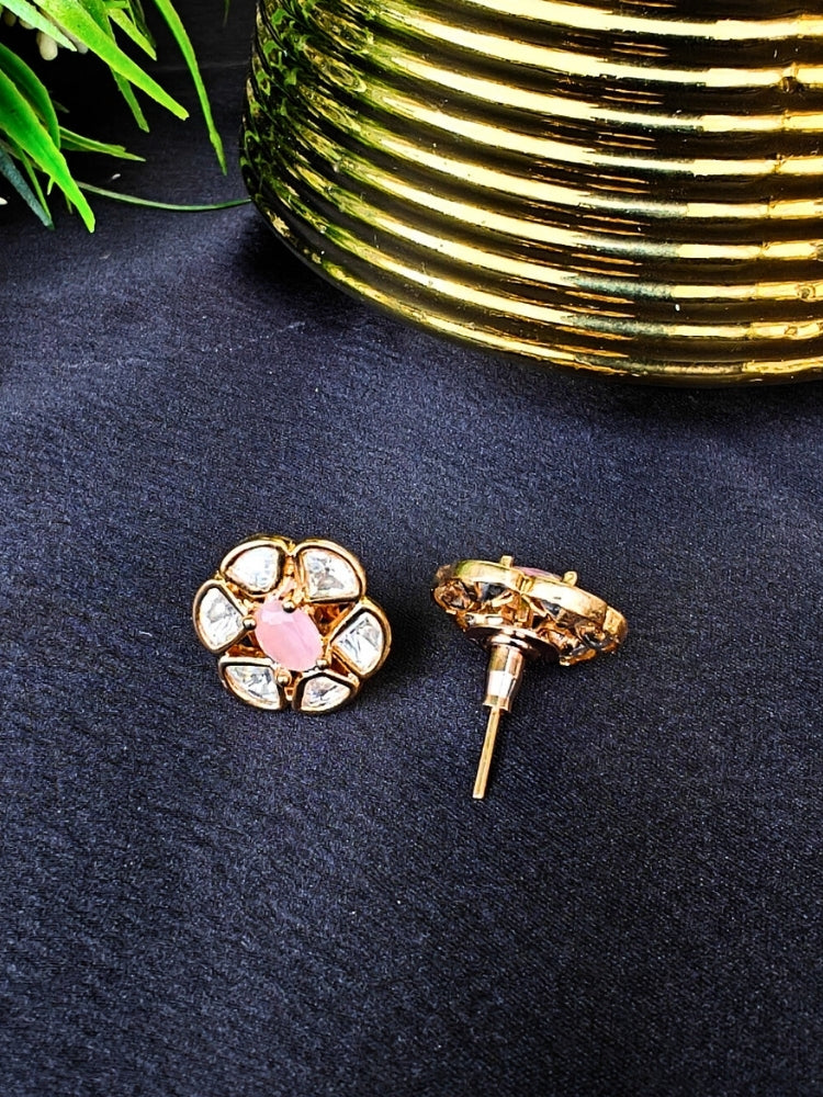 The Mint Pink Daffodil stud Earrings feature gold flower-shaped brass settings with clear American Diamond petals and a Mint Pink stone center, displayed on a Black surface with Golden Aceent in the background