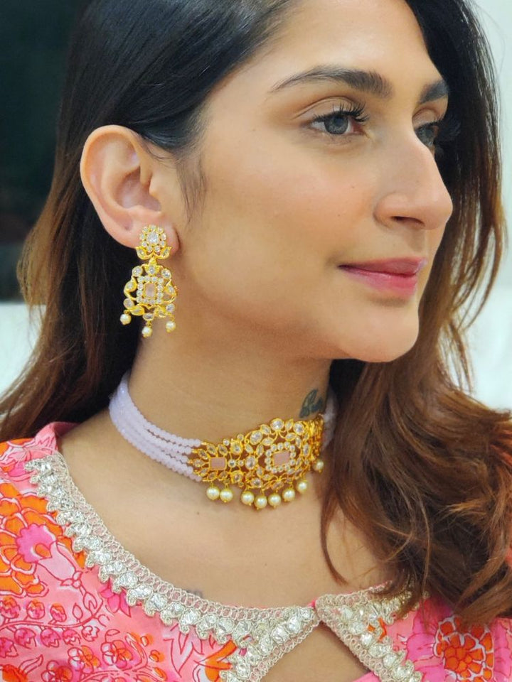A woman with long brown hair wears the Mint Pink Sarah choker Necklace Set, featuring an ornate crystal-beaded choker with gold and pearl details and matching gold earrings. She has a neutral expression and wears a light-colored top.