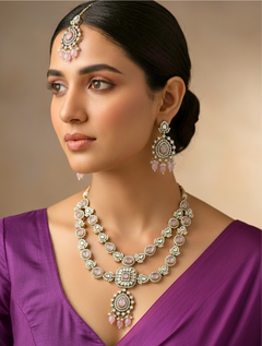 Close-up of a woman wearing an ornate traditional Mint Pink Diamond Collar Layered jewellery set and earrings and maangtikka with Kundan, American Diamonds, Tumble stones, Black Polish and Colored Stones. A woman wearing a luxury American diamond necklace set styled beautifully for a wedding guest look in India. Close-up of a bridal look featuring an anti-tarnish American diamond artificial necklace.